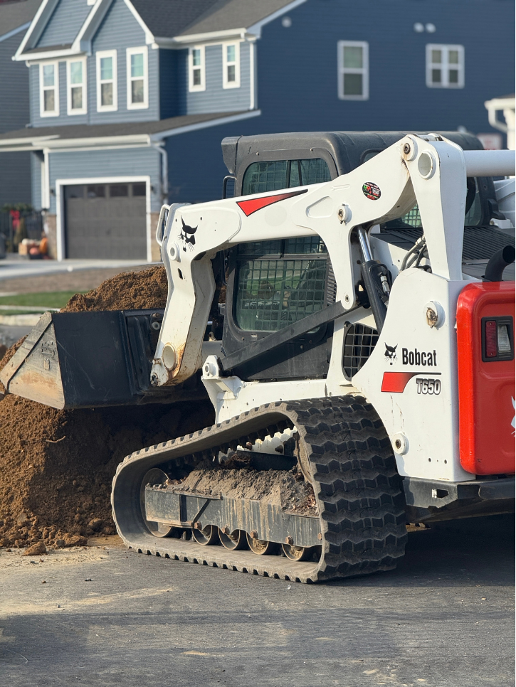 Bobcat moving dirt on driveway
